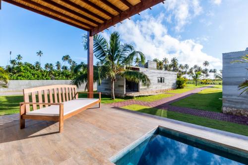 un patio al aire libre con banco y piscina en Bahay Tatu, en Porto de Pedras