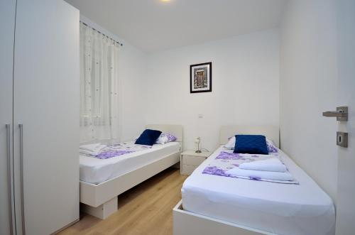 two beds in a room with white walls and wooden floors at The Nikolic Suites - Villa Wögenstein in Tribunj