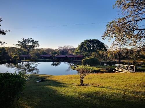 a bridge over a pond with a house in the background at Hotel Rincón de la Vieja Lodge in Liberia