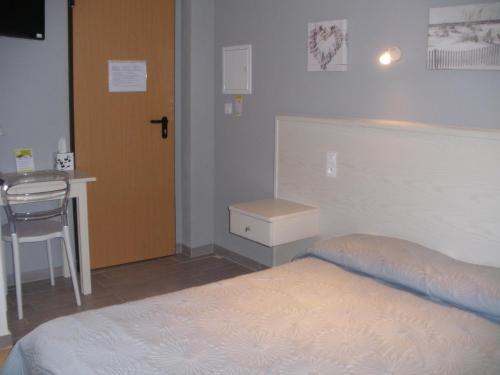 a bedroom with a bed and a table and a chair at Hôtel Casa di Mama in Porto-Vecchio