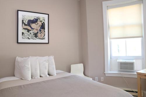 een slaapkamer met een wit bed met een foto aan de muur bij Stylish Downtown Studio in the South End, C. Ave #1 in Boston