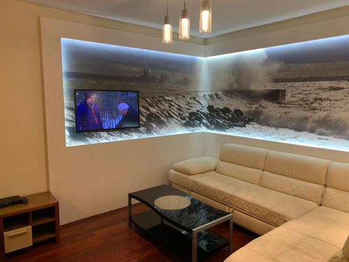 a living room with a couch and a tv on a wall at Sea Towers in Gdynia