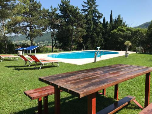a picnic table in the grass next to a pool at Welcome Traveller VILLA LEDA in Garda