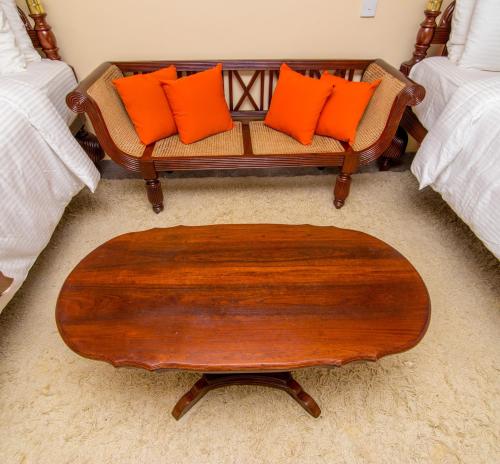 a couch with orange pillows and a wooden table at The Forest and Lake by Schofieldshire in Nuwara Eliya