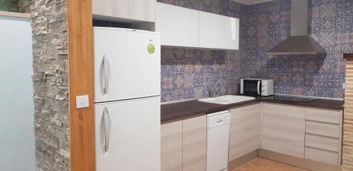 a kitchen with a white refrigerator and a sink at Apartamentos Montgò in Denia