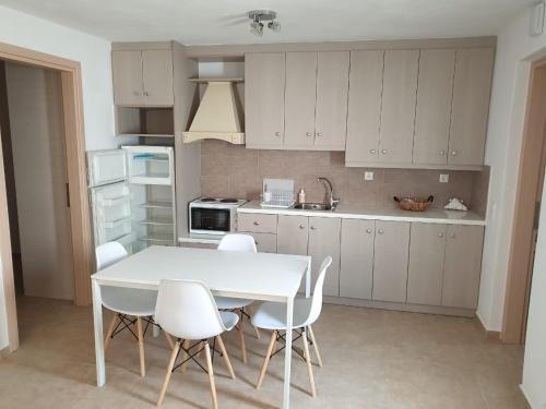 a kitchen with a white table and white chairs at Maya Apartments in Dexamenes