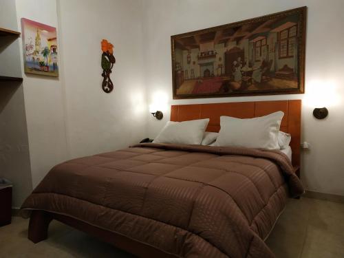 a bedroom with a bed with a painting on the wall at Casa India Catalina in Cartagena de Indias