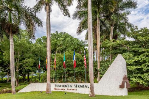 a monument with flags in a park with palm trees at Hacienda Uxmal Plantation & Museum in Uxmal