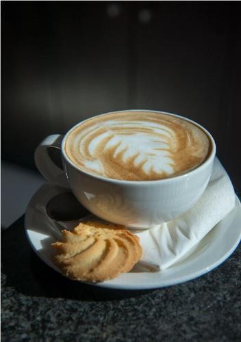 a cup of coffee on a plate with a cookie at Park Inn by Radisson, Lagos Victoria Island in Lagos