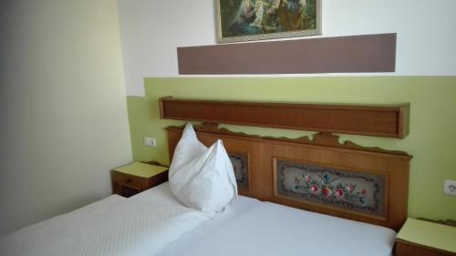 um quarto com uma cama branca e uma cabeceira em madeira em Pension Restaurant Meran em Abtenau