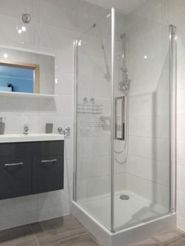 a white bathroom with a shower and a sink at Apartament Marzenie 6 - Opole in Opole