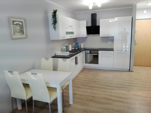 オポーレにあるApartament Marzenie 6 - Opoleの白いキャビネット、白いテーブルと椅子付きのキッチン