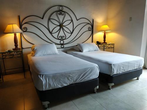 two beds sitting in a room with two lamps at Casa India Catalina in Cartagena de Indias