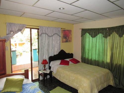1 dormitorio con 2 camas y una ventana con cortinas verdes en Nelyza's Suites & Adventure en Puerto Ayora