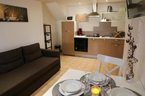 Gîte LE JARDINIER في إبينال: غرفة معيشة مع أريكة وطاولة مع كؤوس للنبيذ