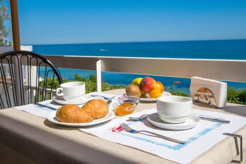 a table with a breakfast of croissants and fruit at Hotel Adler in Gabicce Mare