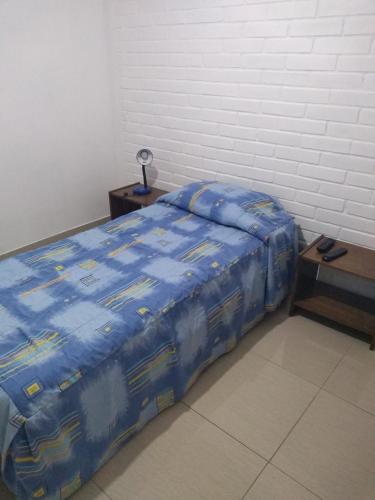 a bed with a blue comforter in a room at Hotel Angamos in Santiago