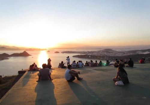 a group of people sitting on the edge of a rock overlooking the water at Brasileranza Hostel in Niterói