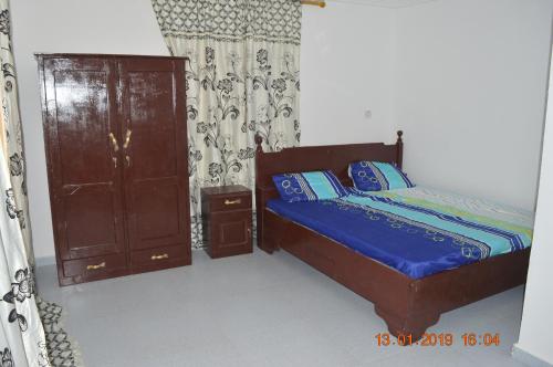 a bedroom with a bed and a wooden cabinet at Sukuta Nema Guest House in Banjul