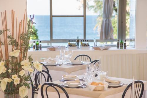 a table with chairs and plates and wine glasses at Hotel Adler in Gabicce Mare