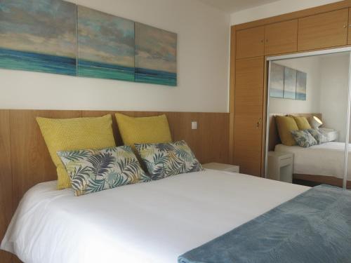 a bedroom with a large white bed with yellow pillows at OLY BEACH in Nazaré