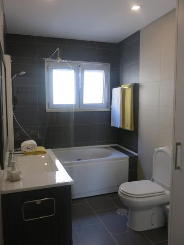 a bathroom with a tub and a toilet and a sink at OLY BEACH in Nazaré