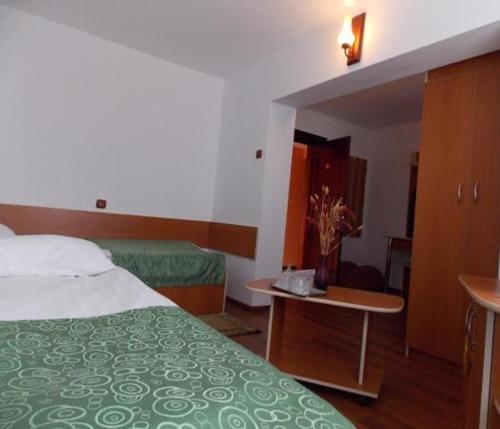 a hotel room with a bed and a desk and a table at Hotel Amadeo in Iaşi