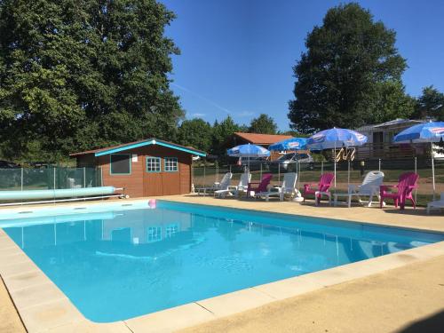 une piscine avec chaises et parasols dans l'établissement Camping des Papillons, à Lalizolle