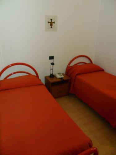 two beds in a room with red sheets at Ospitalità San Tommaso d'Aquino in Bologna