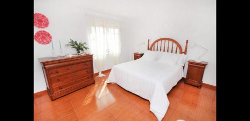 een slaapkamer met een wit bed en een houten dressoir bij Garda in Santa Pola