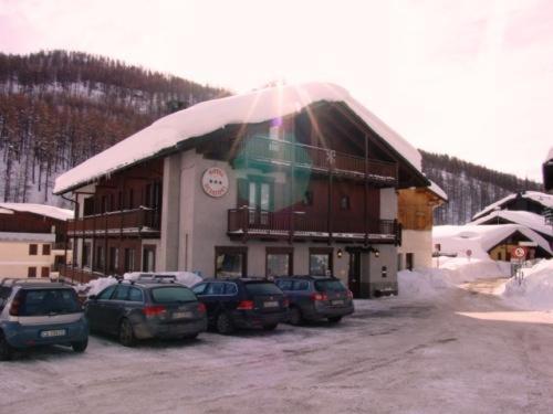 a snow covered building with cars parked in front of it at Hotel Sciatori in Sestriere