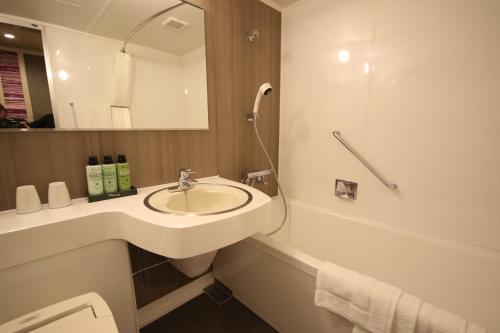 ein Badezimmer mit einem Waschbecken, einem Spiegel und einer Badewanne in der Unterkunft Kita Hotel in Morioka