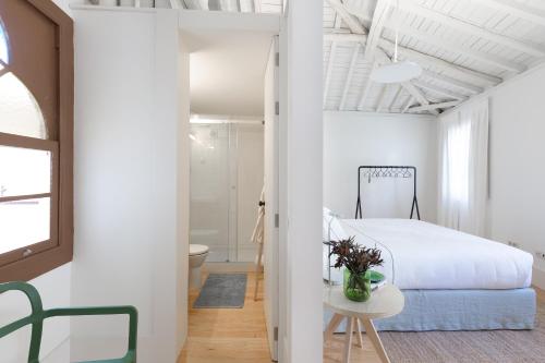 a white bedroom with a bed and a bathroom at B28 Apartments Porto in Porto