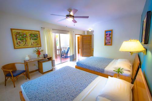 a bedroom with two beds and a table and a chair at Hotel Restaurant Cyvadier Plage in Jacmel