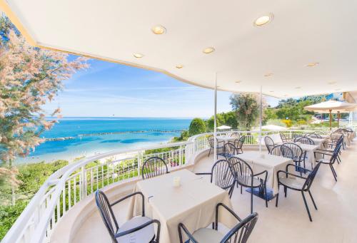 a balcony with tables and chairs and the ocean at Hotel Adler in Gabicce Mare
