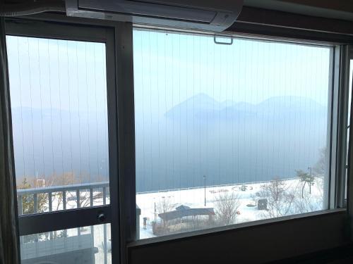a window with a view of a snow covered mountain at Granvillage Toya Daiwa Ryokan Annex in Lake Toya