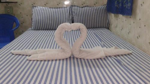 two towel swans making a heart on a bed at SIU Mansion in Chennai