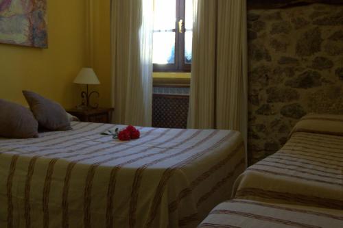 a hotel room with two beds and a flower on the bed at Hostal Rural Elosta in Lekunberri