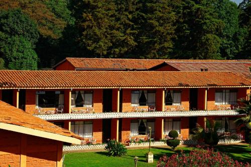 um edifício de tijolos vermelhos com árvores ao fundo em Hotel Pie de la Sierra em Uruapan del Progreso