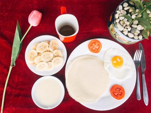 a plate with an egg and bananas and tomatoes on a table at Mường Trà Garden Homestay in Làng Cac