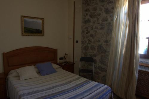 a bedroom with a bed with a blue blanket and a window at Hostal Rural Elosta in Lekunberri