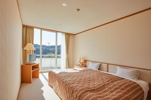 a hotel room with a bed and a large window at Kamogawa Country Hotel in Kamogawa
