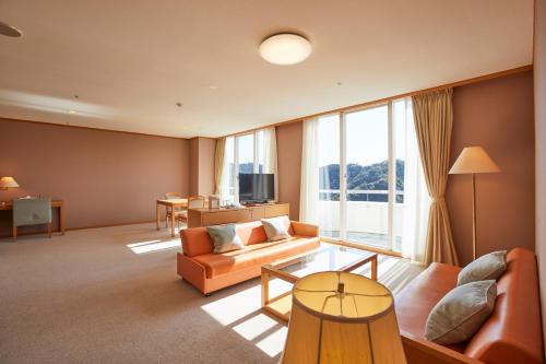 a living room with orange furniture and a large window at Kamogawa Country Hotel in Kamogawa