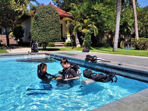 dos personas en el agua en una piscina en La Bila Dive Resort Amed, en Amed