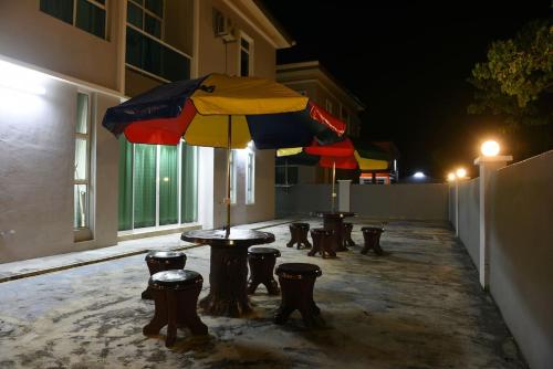 a group of tables and chairs with an umbrella at Langkawi Cozy Holiday Home at Taman Indah by Zervin in Kuah