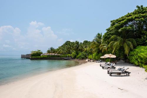 a beach with chairs and umbrellas and the ocean at Song Saa Private Island in Song Saa Private Island
