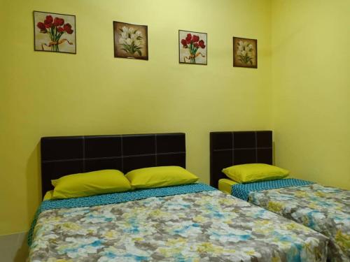 a bedroom with two beds and pictures on the wall at Mutiara Inn GuestRoom in Kampung Gurun