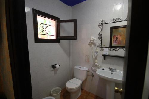 a bathroom with a toilet and a sink and a window at Hotel Copacabana Tarifa Beach in Tarifa
