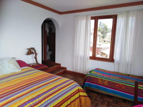 1 dormitorio con cama y ventana en Hostal Inti Wayra, en Comunidad Yumani