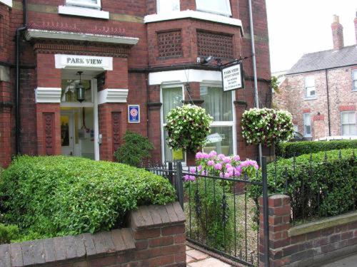 una casa di mattoni con una recinzione e fiori di fronte di Park View Guest House a York